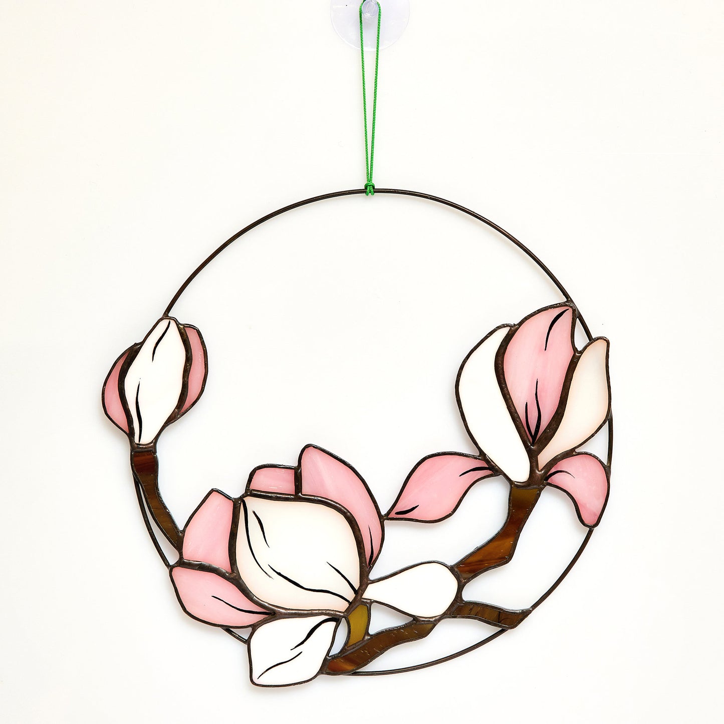 A stained glass magnolia window hanging on the white wall