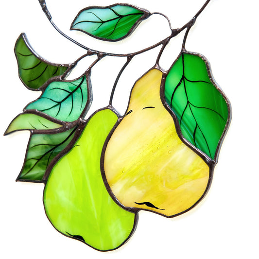 A hand-crafted stained glass suncatcher in the shape of a pear branch with green leaves and yellow fruit.
