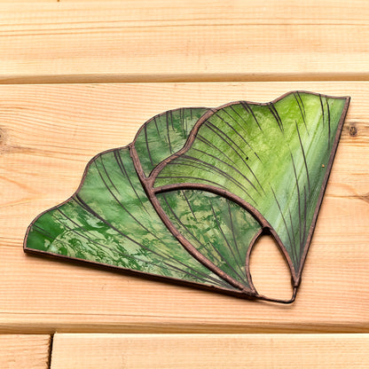 A pair of handcrafted stained glass bookends in the shape of Ginkgo leaves, set against a wooden background.