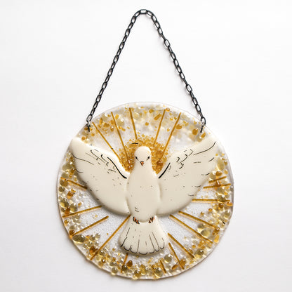 A round fused glass sun catcher with the Holy Spirit symbol, featuring a white bird with gold and yellow accents on a chain for hanging.
