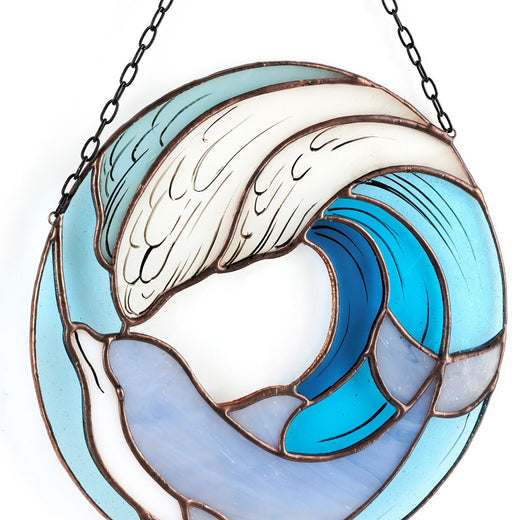 A handmade stained glass suncatcher featuring a dolphin leaping through blue and white waves.