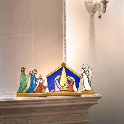 Stained glass nativity set depicting the Holy Family, shepherds, angels, and the three magi, placed on a wooden platform.
