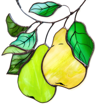 A hand-crafted stained glass suncatcher in the shape of a pear branch with green leaves and yellow fruit.